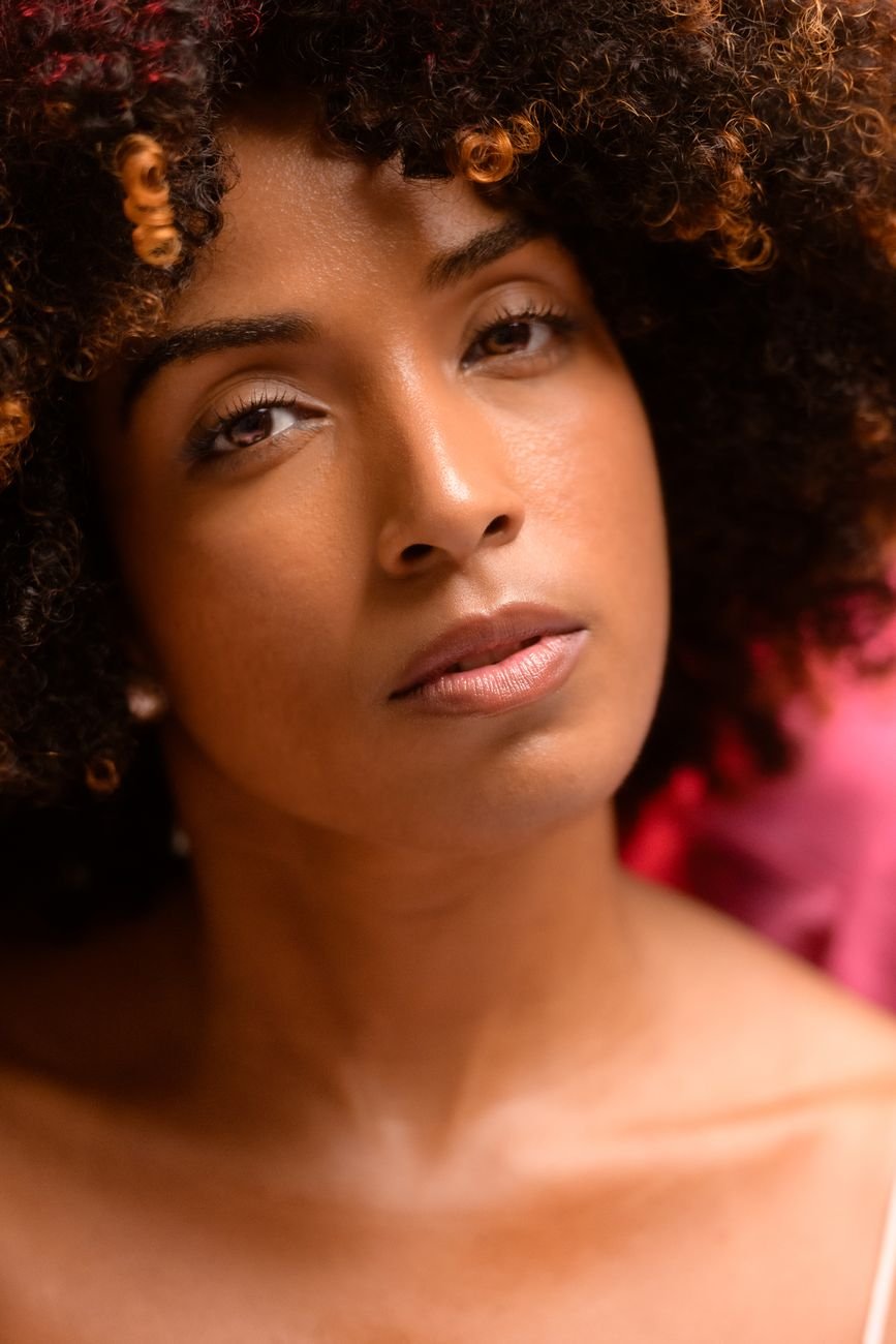 Close-up portrait of a woman with natural curly hair in warm lighting