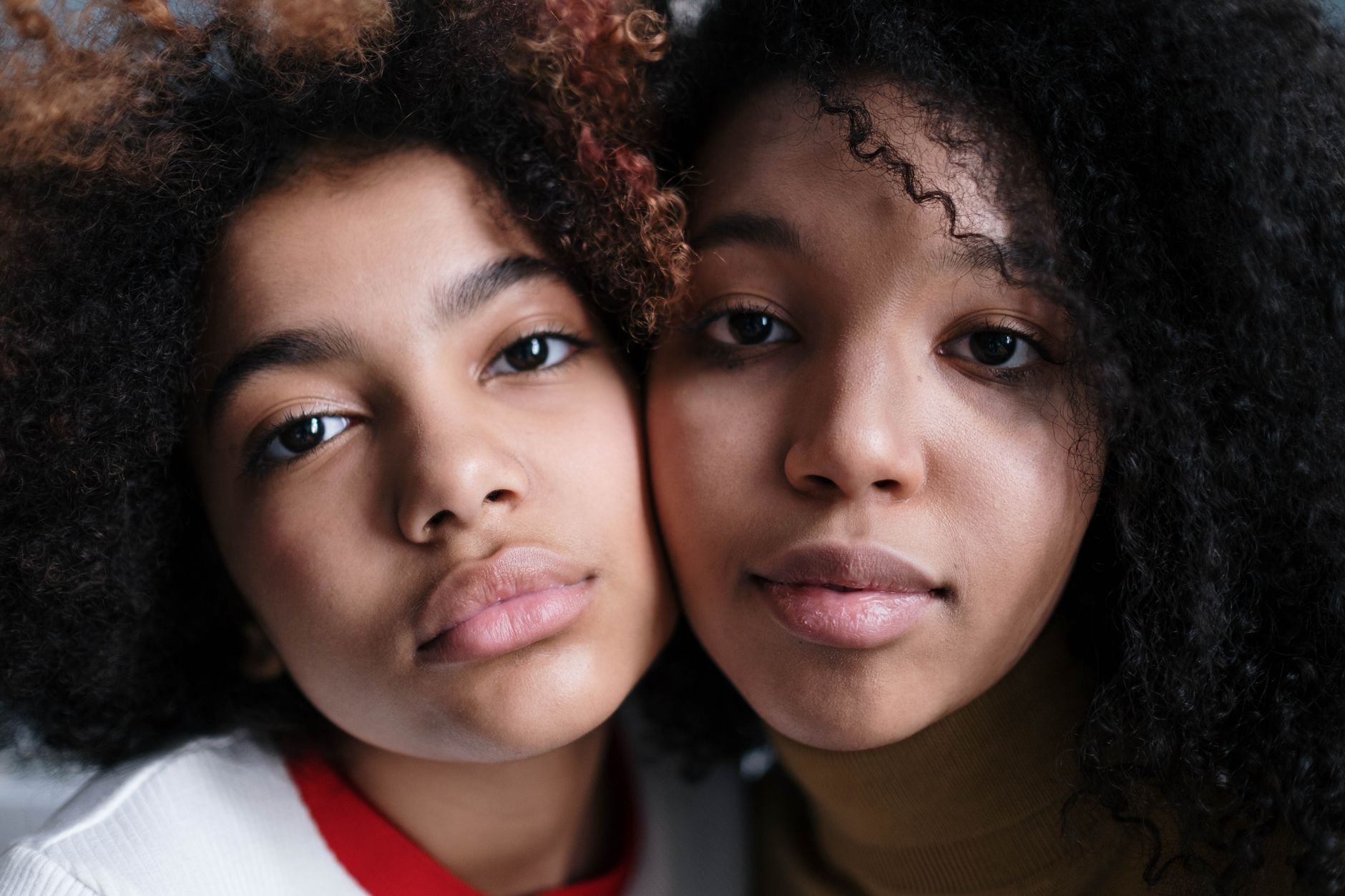 Two women with natural hair textures, warm editorial portrait